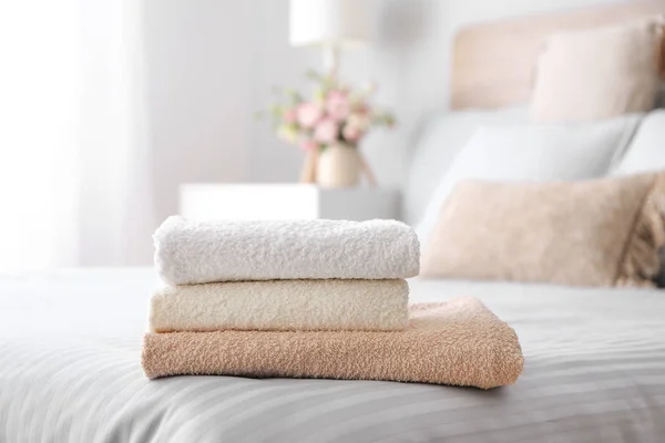 Stack of clean towels on bed — Stock Photo, Image