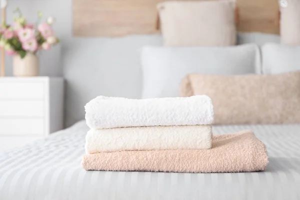 Stack of clean towels on bed — Stock Photo, Image