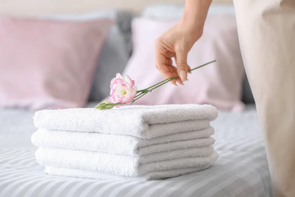 Female housekeeper putting flower onto clean towels on bed — Stock Photo, Image