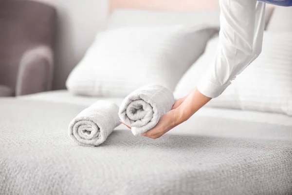 Female housekeeper putting clean towel on bed — Stock Photo, Image