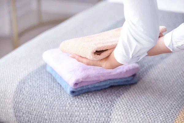 Empregada feminina colocando toalhas limpas na cama — Fotografia de Stock