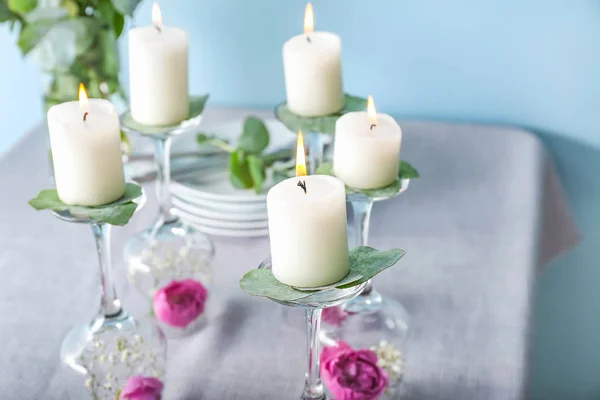 Glasses with flowers and burning candles on table — Stock Photo, Image