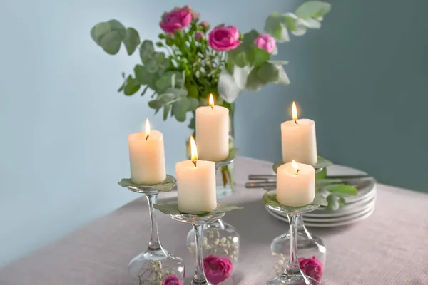 Platos, flores y vasos con velas encendidas en la mesa — Foto de Stock
