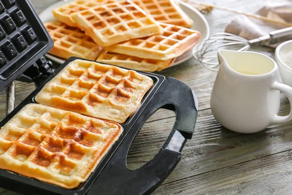 Modern maker with waffles on wooden table — Stock Photo, Image