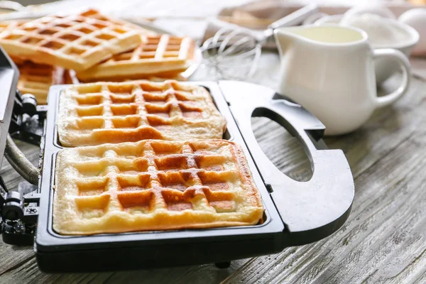 Modern maker with waffles on wooden table, closeup — Stock Photo, Image