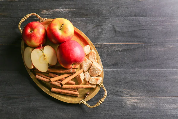 Tray with fresh apple, cinnamon and sugar on dark table — Stock Photo, Image