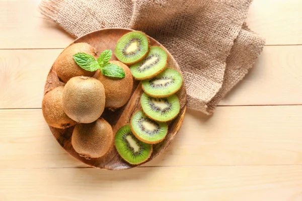 Plate with tasty ripe kiwi on wooden background — Stock Photo, Image