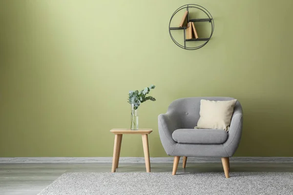 Soft armchair and table with eucalyptus branches in interior of room — Stock Photo, Image