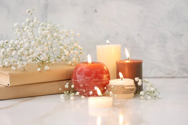 Beautiful burning candles, books and flowers on table — Stock Photo, Image