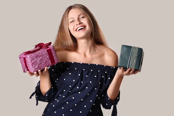 Beautiful young woman with gifts on grey background — Stock Photo, Image