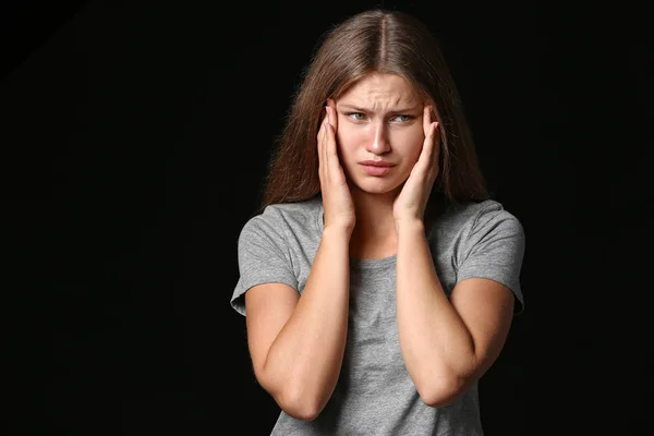 Gestresste junge Frau auf dunklem Hintergrund — Stockfoto