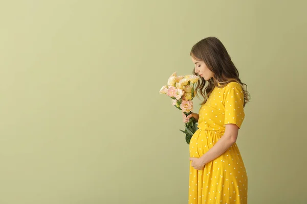 Hermosa mujer embarazada con ramo de flores sobre fondo de color —  Fotos de Stock