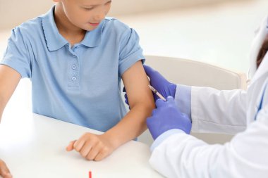 Doktor küçük çocuğu klinikte aşılıyor.