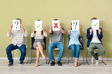 Gençler kapalı koltuklarda otururken farklı işaretler ile kağıt levhalar tutan genç insanlar. İş görüşmesi kavramı