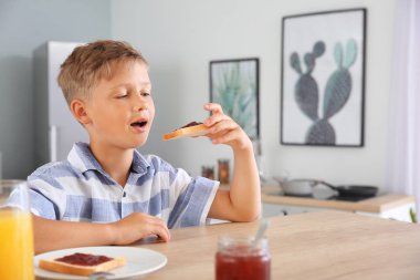 Komik küçük çocuk mutfakta reçel ile lezzetli tost yeme