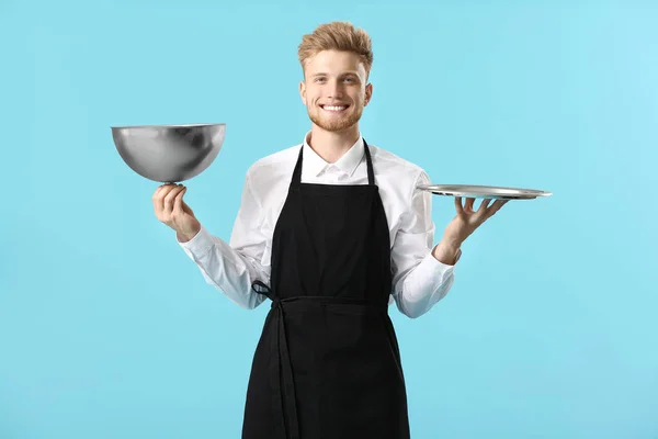 Guapo chef masculino con bandeja y cloche sobre fondo de color —  Fotos de Stock