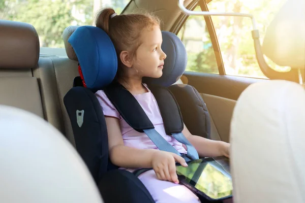 Little girl with tablet computer buckled in car safety seat — Stock Photo, Image