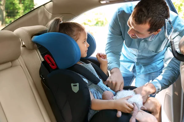 Father buckling his little daughter in car safety seat — Stock Photo, Image