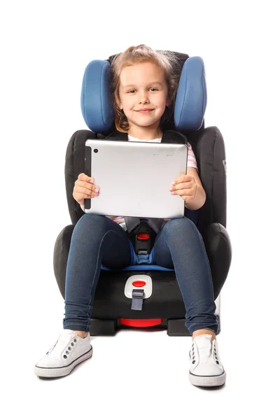 Fetiță cu calculator comprimat catarat în scaun de siguranță auto pe fundal alb — Fotografie, imagine de stoc