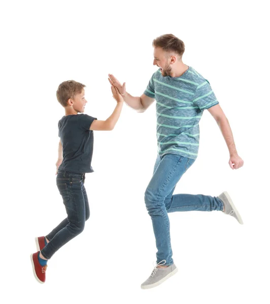 Jumping father and son giving each other high-five on white background — Stock Photo, Image