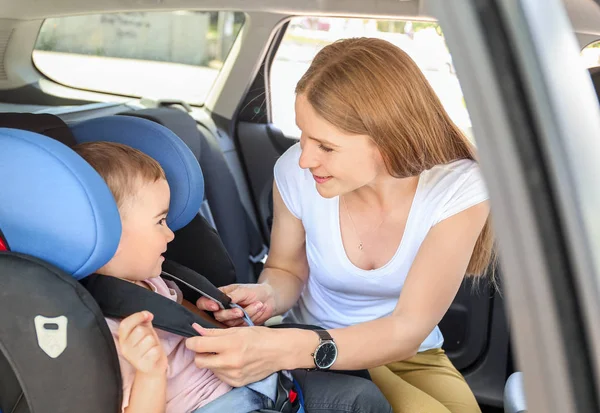 Mother buckling her little son in car seat — Stock Photo, Image