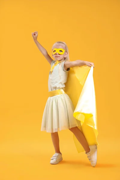 Cute little girl dressed as superhero on color background — Stock Photo, Image