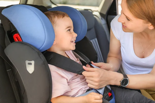 Mother buckling her little son in car seat — Stock Photo, Image