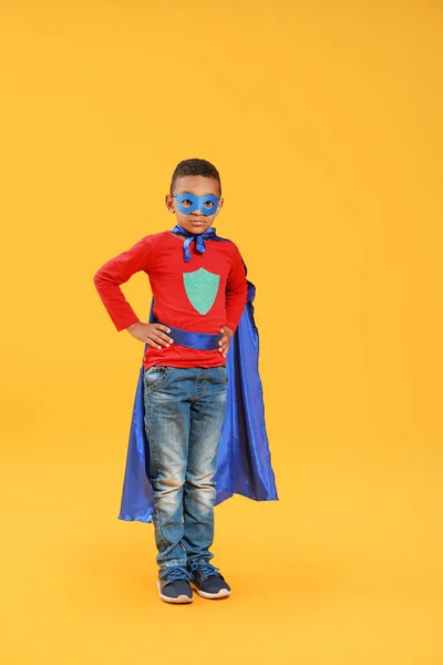 Schattige Afro-Amerikaanse jongen gekleed als superheld op kleur achtergrond — Stockfoto