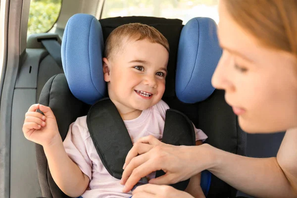 Mother buckling her little son in car seat — Stock Photo, Image