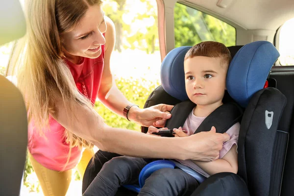 Мать пристегивает своего маленького сына на автомобильном сидении — стоковое фото