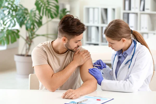 Doutor vacinando jovem na clínica — Fotografia de Stock