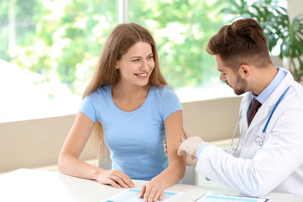 Doctor vaccinating young woman in clinic — Stock Photo, Image