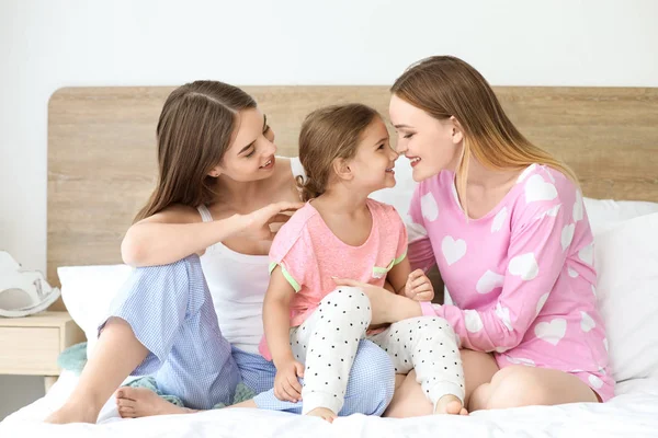 Happy lesbian couple with little daughter in bedroom — Stock Photo, Image