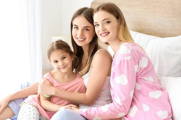 Happy lesbian couple with little daughter in bedroom — Stock Photo, Image