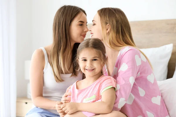 Happy lesbian couple with little daughter in bedroom — Stock Photo, Image