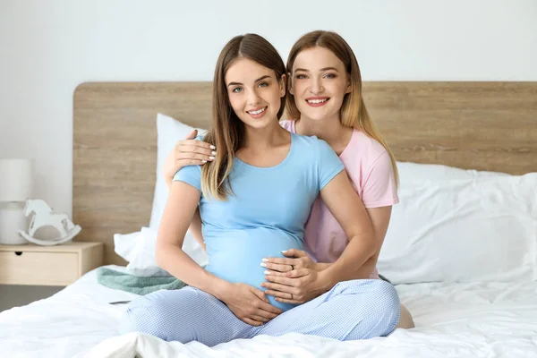Счастливая беременная лесбийская пара в спальне — стоковое фото