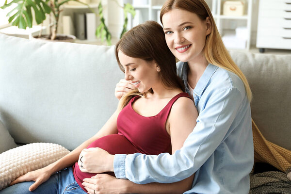 Happy pregnant lesbian couple at home