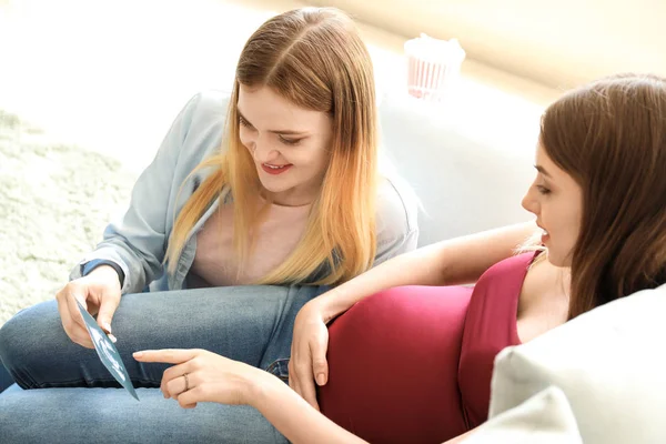 Pregnant lesbian couple with sonogram image at home — Stock Photo, Image