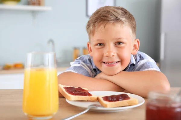 Zabawny mały chłopak jedząc smaczne tosty z dżemem w kuchni — Zdjęcie stockowe