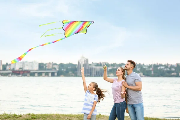 Happy family flying kite near river — Stock Photo, Image