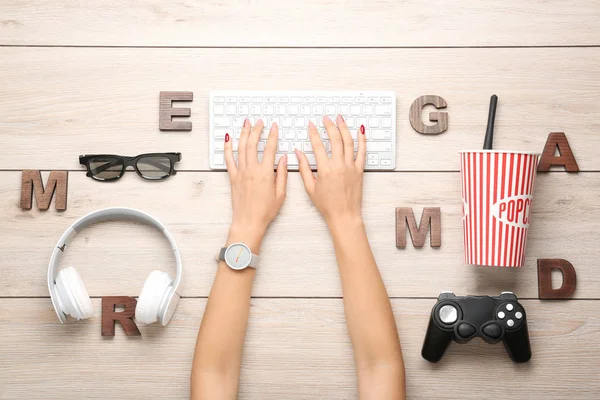 Female hands with computer keyboard, joypad, headphones and letters on wooden background — Stock Photo, Image