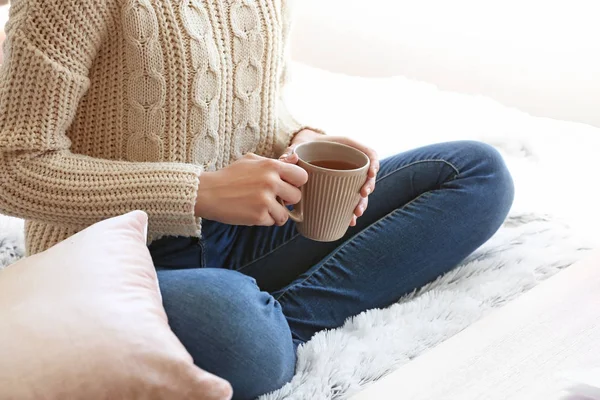 Mujer joven bebiendo té caliente en casa — Foto de Stock