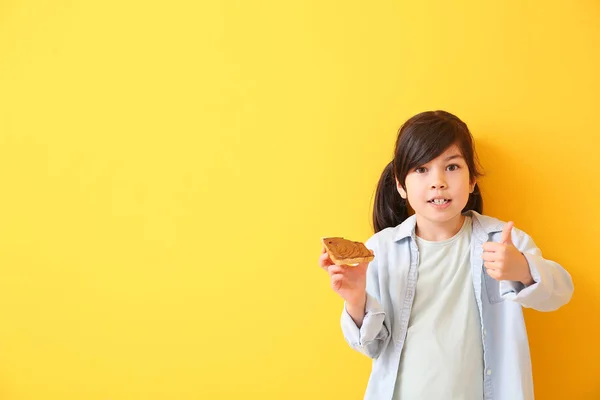 Engraçado menina segurando saborosa torrada com chocolate se espalhando no fundo de cor — Fotografia de Stock