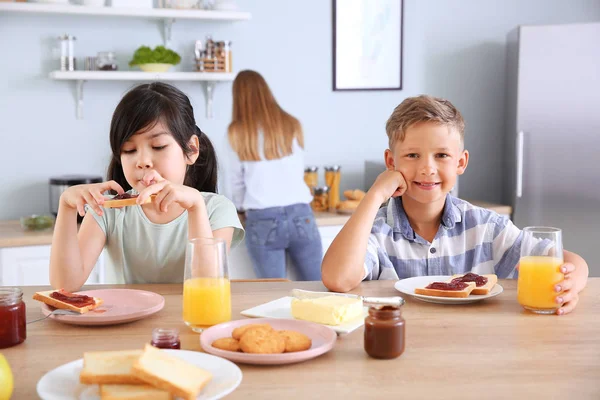 Zábavné děti, které v kuchyni jedí chutné přípitky — Stock fotografie