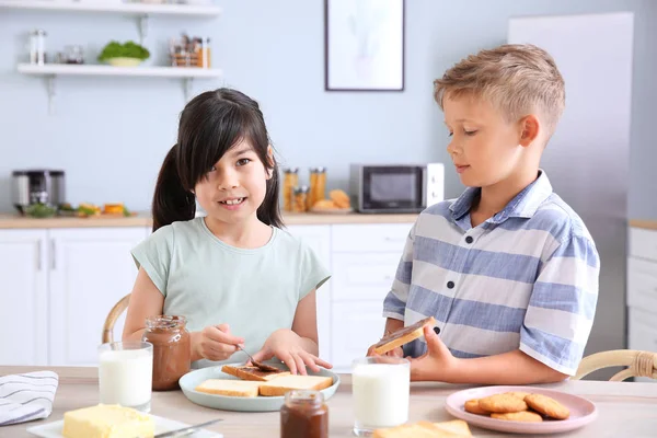 Funny little children eating tasty toasts in kitchen — Stock Photo, Image
