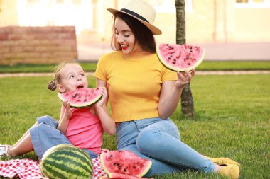 Sevimli küçük kız ve annesi parkta tatlı karpuz yeme