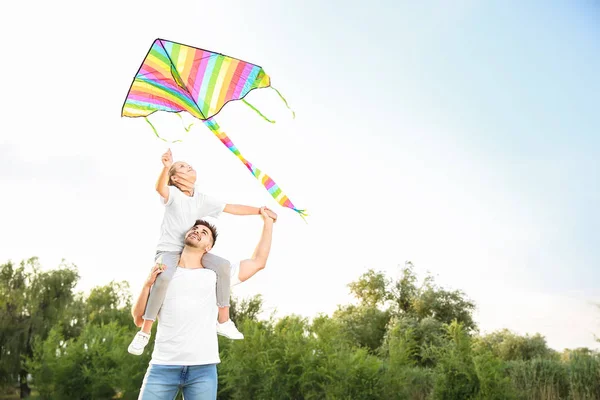 Young man with little daughter flying kite outdoors — Stock Photo, Image