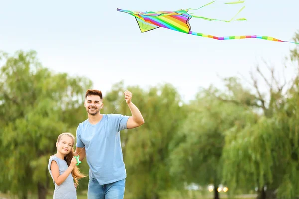 Young man with little daughter flying kite outdoors — Stock Photo, Image