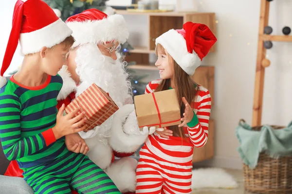 Weihnachtsmann und seine kleinen Helfer mit Geschenken im weihnachtlich dekorierten Raum — Stockfoto