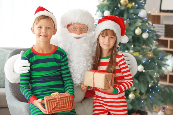 Weihnachtsmann und seine kleinen Helfer mit Geschenken im weihnachtlich dekorierten Raum — Stockfoto